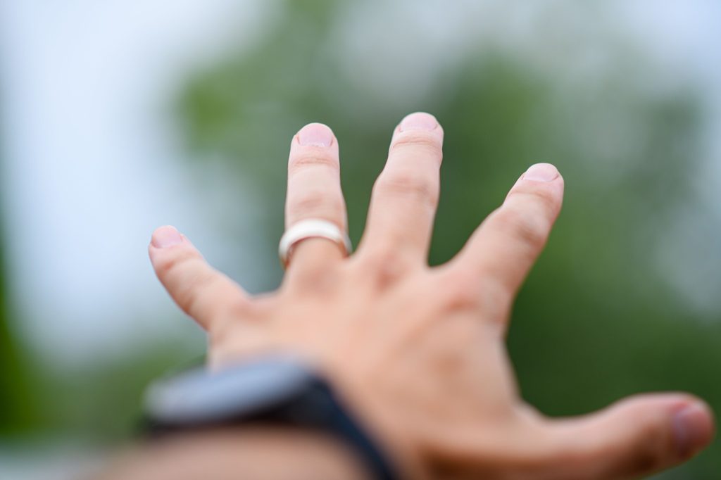 Outstretched hand wearing a ring and smartwatch outdoors